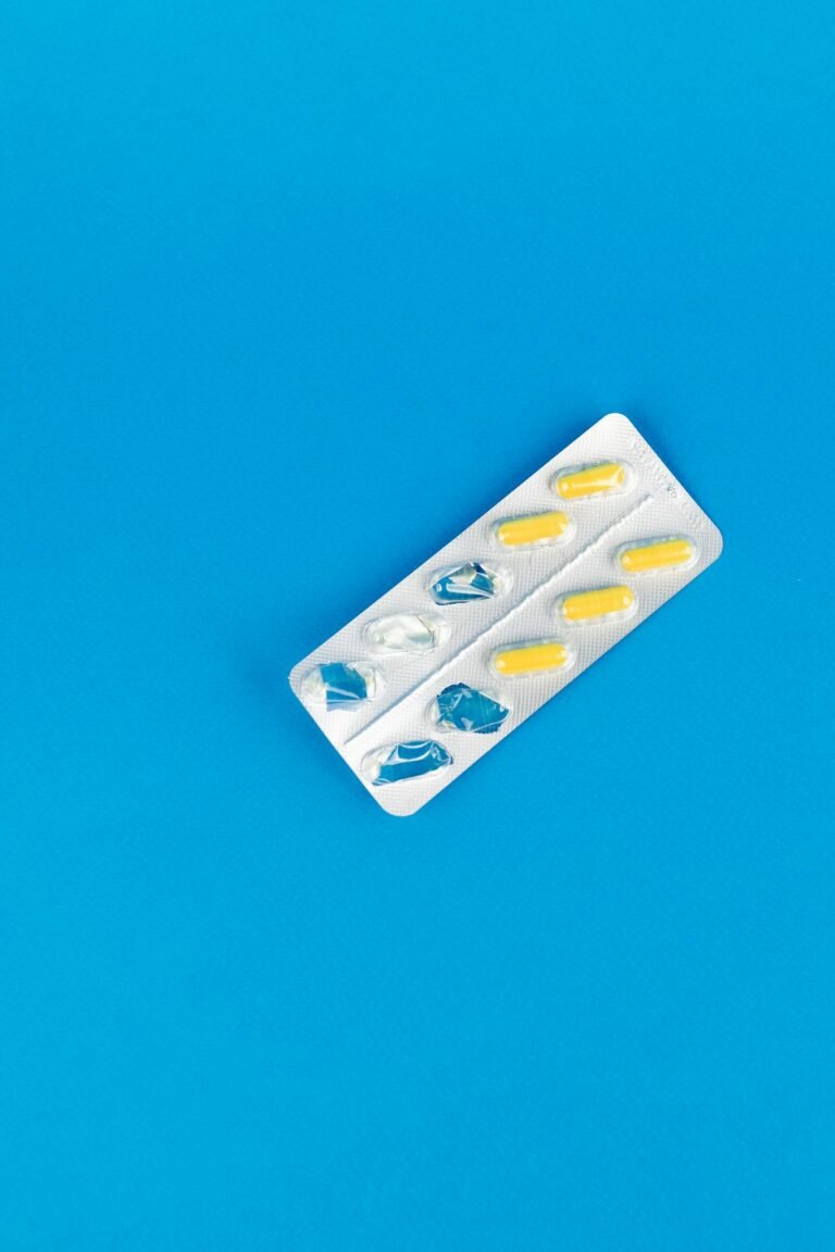 A blister pack of pills with blue and yellow capsules on a vibrant blue background.